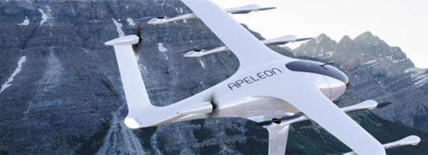 A white ApeleoN electric aeroplane flies in front of a rocky mountain peak under a clear sky.