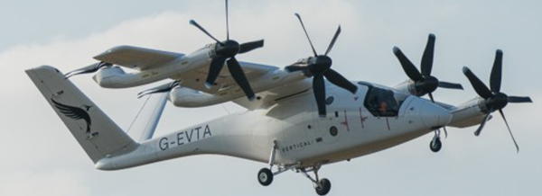 A white electric vertical take-off aircraft with four large rotors flies against a partly cloudy sky.