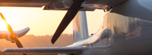 Close-up of an aeroplane with visible propellers at sunset, with sunlight shining through the background.